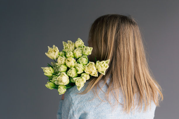 女性手中捧着郁金香花束，从背后眺望。图片下载