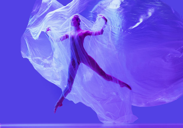 美丽柔韧的女人的肖像，芭蕾舞演员与布料在霓虹灯紫色工作室背景跳舞。时尚、风格、艺术、美图片下载