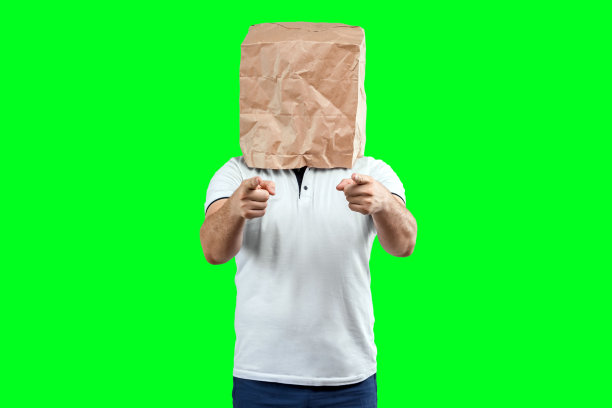 男人在头上套个纸袋，用手指指着你，激励他们。孤立在绿色背景上，图像易于裁剪使用的任何地方，复制空间。图片下载