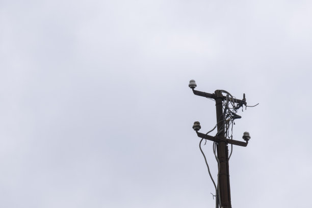 旧的和生锈的灯柱上的电缆和未使用的绝缘体图片下载