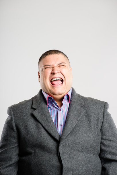 一个英俊的年轻人独自站在演播室里大笑图片下载