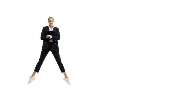 年轻漂亮的女孩穿着商务风格的衣服跳跃与文件夹隔离在白色背景的动态肖像。图片下载