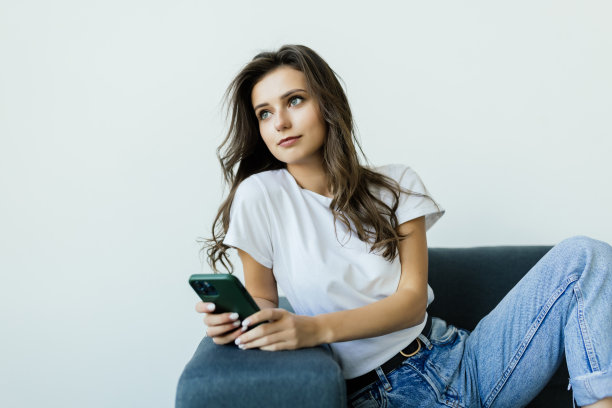 年轻女性看着手机屏幕，阅读带有惊人消息的信息，在社交网络上观看照片或视频内容，购物或玩手机游戏。图片下载