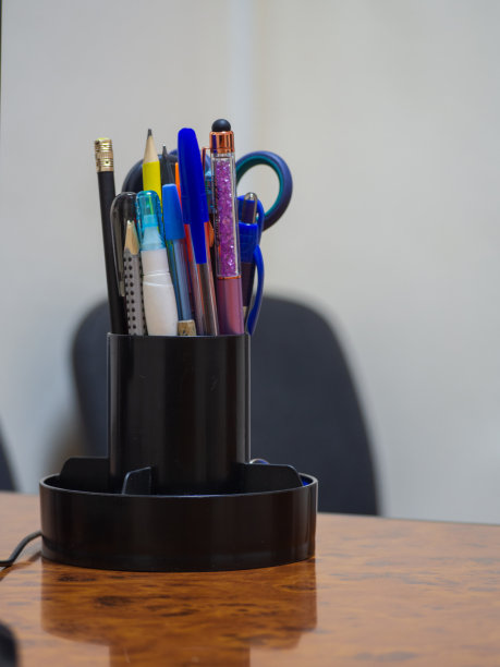 文具放在桌面上的文件夹里。一个组织者的特写与用过的钢笔和铅笔在一个木制的桌子在办公室。办公用品。会议桌上的杯子里有笔图片下载