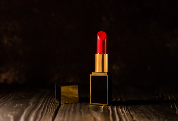 红色口红在一个黑暗的背景上，黑色的金盒子图片下载