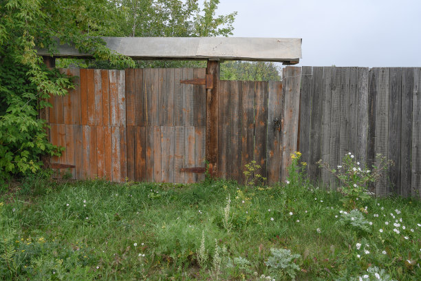 在乌拉尔(俄罗斯)的一个村庄的房子附近，夏天用木板做成的带门的旧木栅栏。图片下载