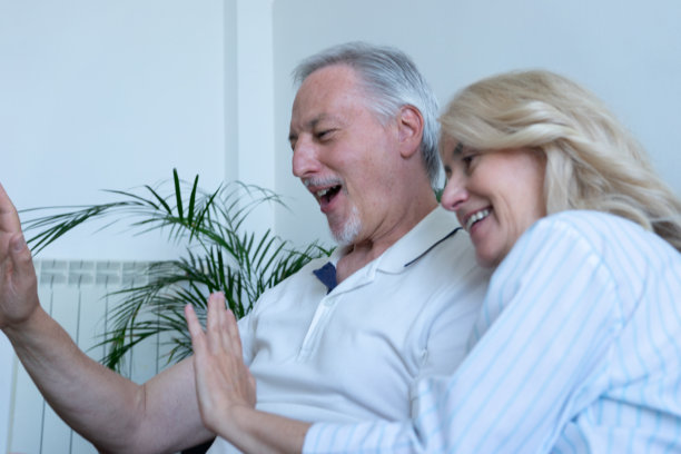 一对老夫妇坐在沙发上用笔记本电脑参加读书俱乐部的视频会议图片下载