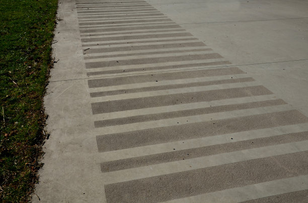 长廊的混凝土表面光滑，有凉棚和木凳。混凝土有些地方粗糙，有条纹。春天，修剪整齐的花圃图片下载