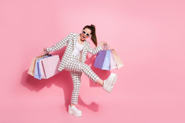 全尺寸照片年轻兴奋快乐微笑的女孩拿着包去购物打折穿运动上衣裤子孤立在柔和的颜色背景图片下载