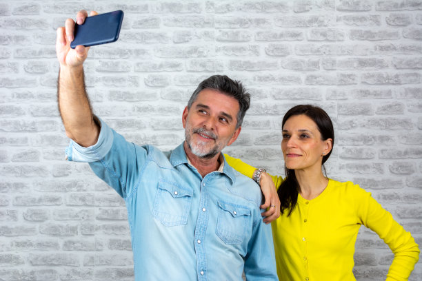 漂亮迷人的迷人的可爱的愉快的愉快的夫妇的肖像握在手中的细胞拍摄自拍图片下载