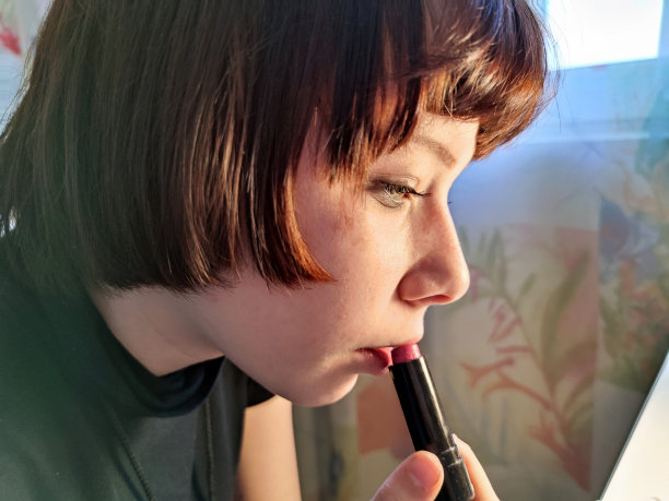 棕色头发的少女用口红涂着嘴唇图片下载