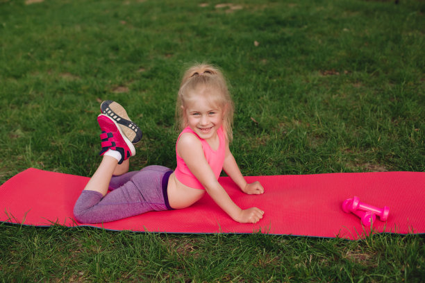 乌克兰美丽的7岁女孩正在河边的绿色田野里健身。图片下载