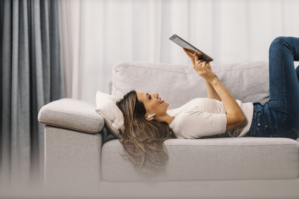 一个女人在家里的沙发上放松着网络视频。图片下载