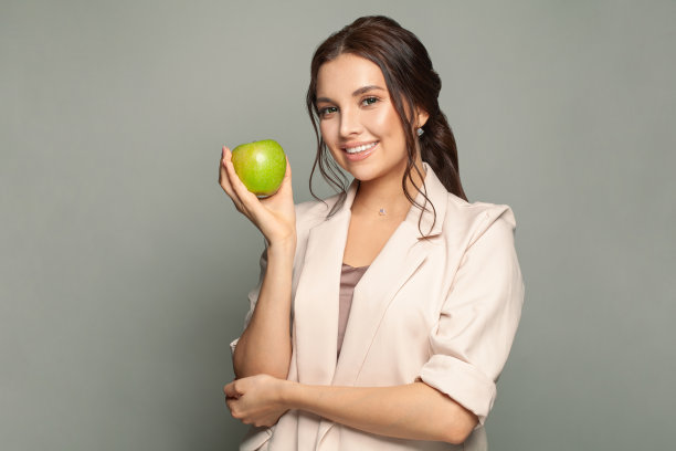 带着苹果微笑的年轻女子。健康的食物图片下载