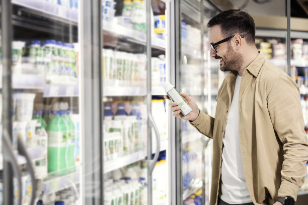 一个微笑的男人在超市挑选酸奶。图片下载