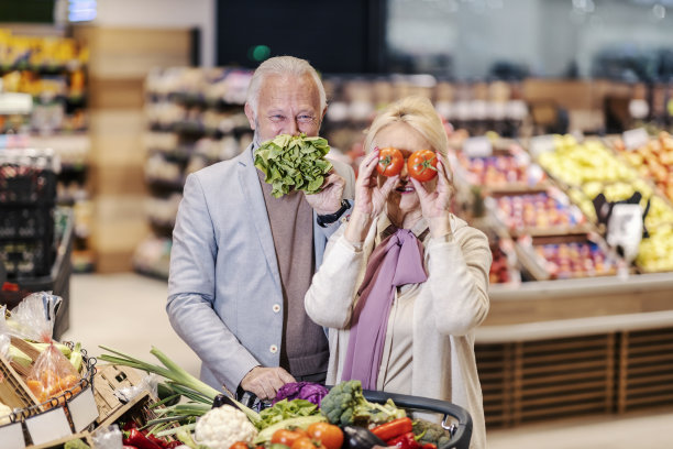 一对老夫妇在超市玩蔬菜。图片下载