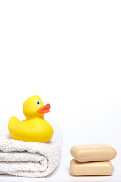 黄色橡胶小鸭在白色毛巾和两块肥皂上。图片下载