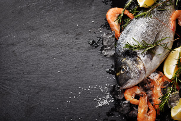 黑色背景上的海鲜。鱼鱼和柠檬虾仁图片下载