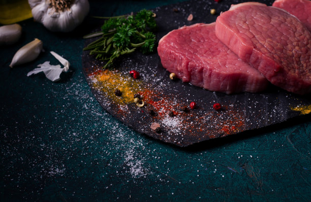 新鲜的生牛肉，大奖章，在黑色石板上，与香料，特写，水平，图片下载