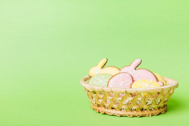 彩色的复活节饼干在篮子里与彩色的复活节彩蛋在彩色的背景。彩色的复活节彩蛋。假日概念与复制空间图片下载