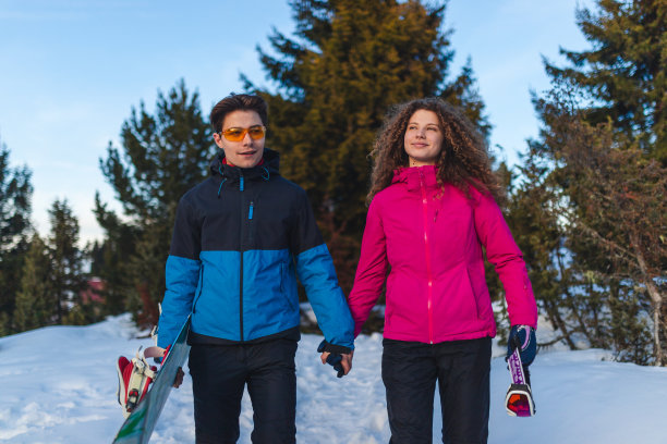 一对美丽的年轻夫妇在雪山上散步，手牵着手，玩着滑雪板图片下载