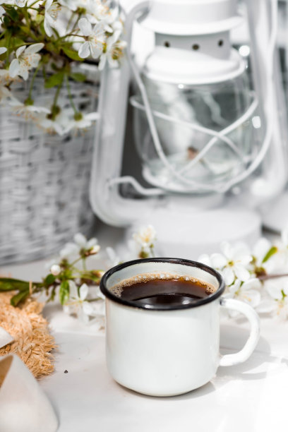 视觉的内容。复古风格的静物画。一杯咖啡，一本旧书，一顶草帽，花园里的木桌上放着一朵樱花。图片下载