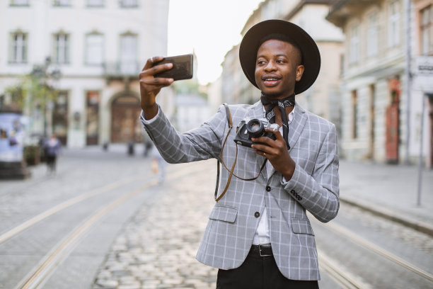 拿着复古相机在手机上自拍的男人图片下载