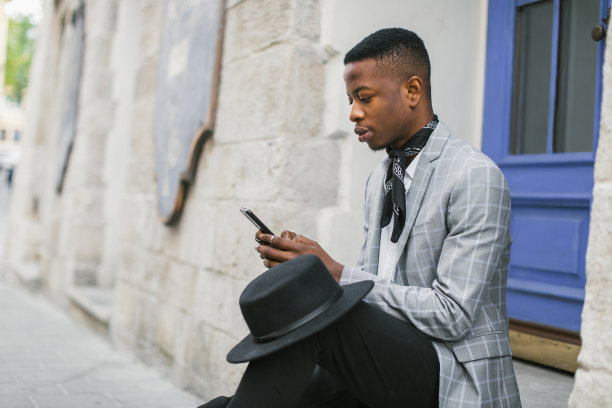 非洲男子在户外使用智能手机的侧视图图片下载