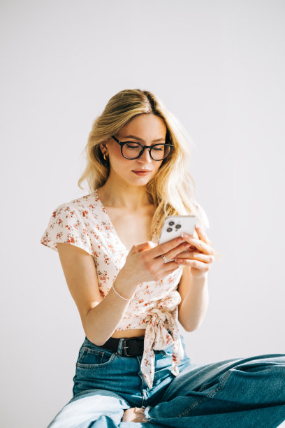 快乐微笑年轻迷人的白人妇女在眼镜使用手机在白色背景。图片下载