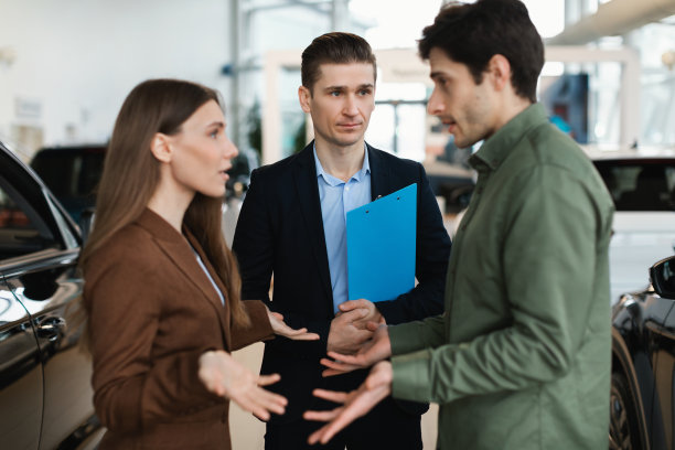 一对年轻的白人夫妇在汽车经销店与汽车销售员交谈时发生了争吵图片下载