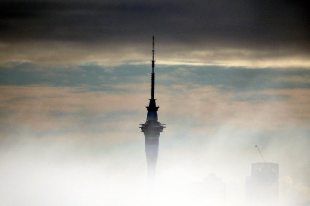 在黑暗多云的天空下，奥克兰的天空塔被浓雾部分遮蔽图片下载