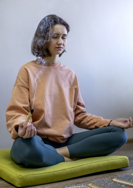 小女孩坐成莲花姿势，双手捧着Palo Santo。香的气味。图片下载