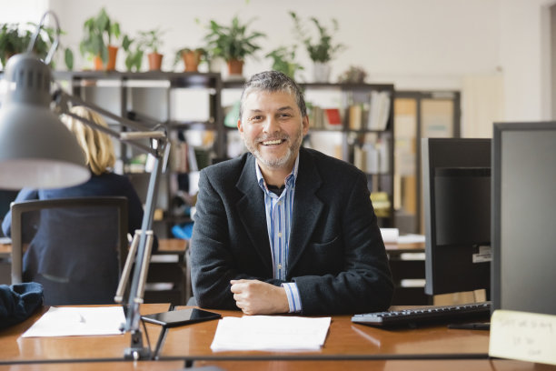 一个成功的成熟商人坐在他的办公桌前的肖像图片下载