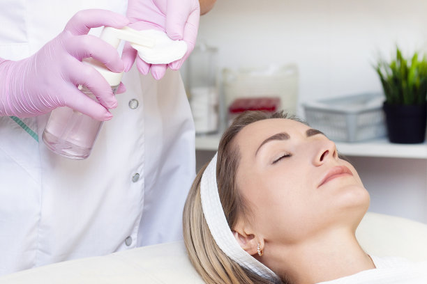 美容。近距离照片可爱的年轻女子与闭着眼睛接受面部清洁程序在美容院。图片下载