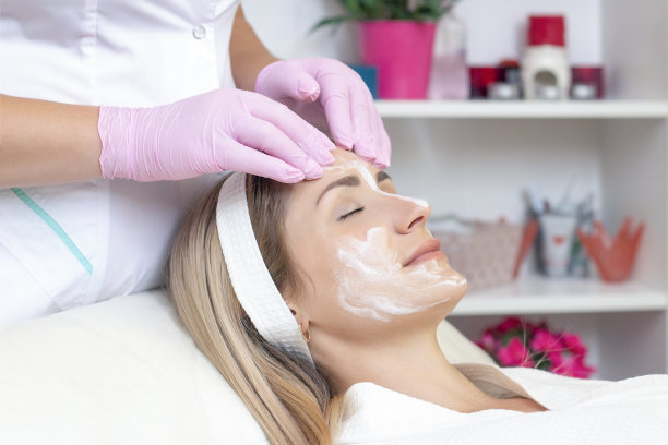 美容。近距离照片可爱的年轻女子与闭着眼睛接受面部清洁程序在美容院。图片下载