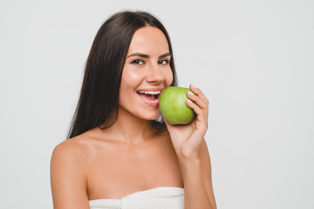 白种人年轻漂亮的女人女孩女性在浴场浴巾吃绿苹果孤立在白色的背景。牙齿微笑，口腔概念。皮肤科，清洁皮肤护理。健康饮食减肥图片下载