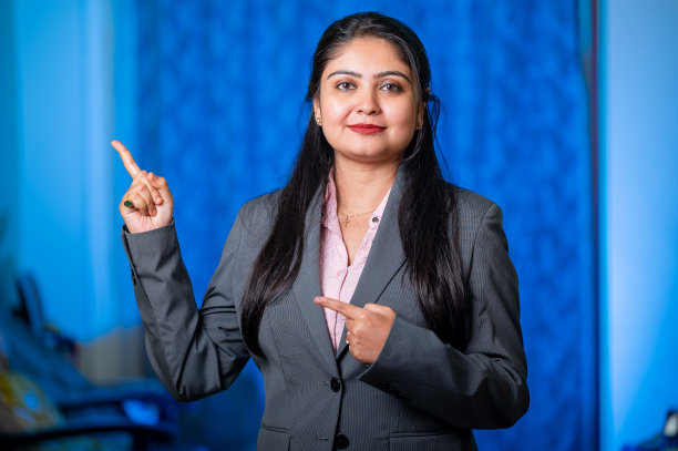 一名年轻女子的肖像，面带微笑，手指指向一边看着相机。图片下载