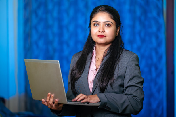 快乐的年轻亚洲/印度女孩的肖像使用笔记本电脑在蓝色背景孤立图片下载