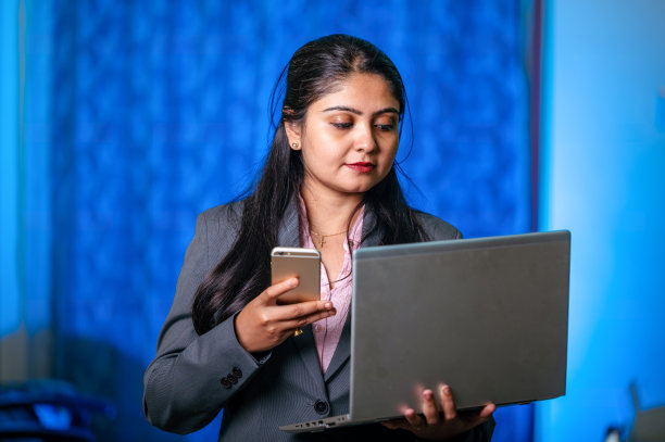 美丽的女商人使用笔记本电脑和智能手机在办公室图片下载