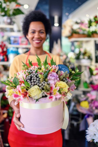 一位非裔美国妇女，手里拿着一个圆形的插花盒。图片下载