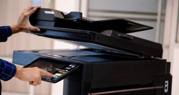 商务人士按下面板上的按钮，在办公室使用影印机或打印机打印输出和扫描文件。图片下载
