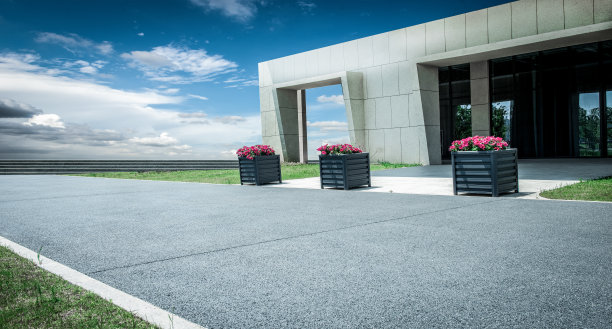 在晴朗的天空下，柏油路前矗立着现代化的建筑图片下载