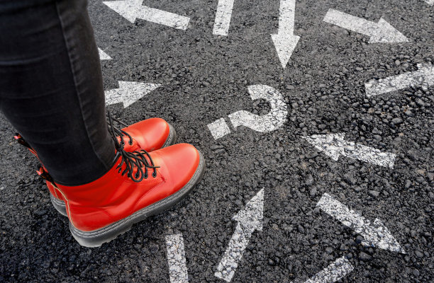 一个穿着靴子的女人站在柏油路上，旁边有许多向不同方向射出的箭和问号图片下载