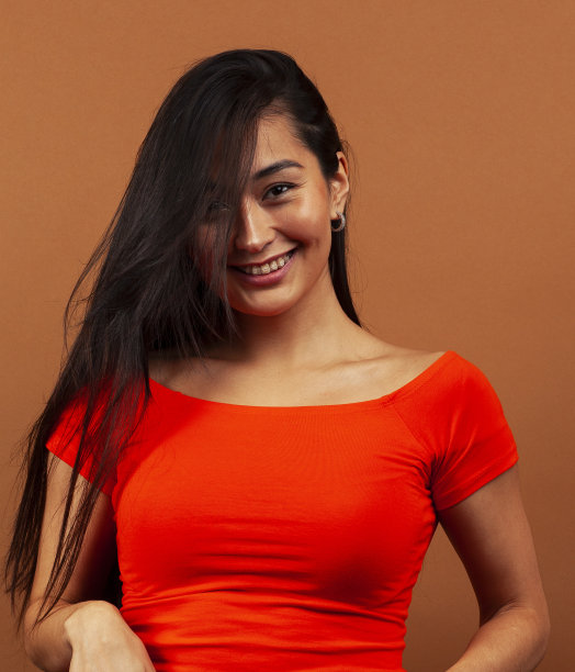 年轻漂亮的亚洲女人开朗的微笑摆姿势在温暖的棕色背景，生活方式的人的概念图片下载