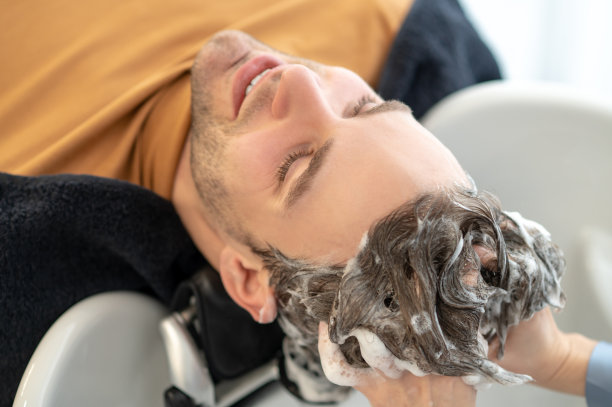 一位男顾客坐在美容院的椅子上洗头发图片下载