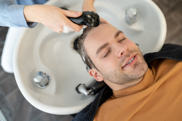 美发师在美容院给男顾客洗头发图片下载