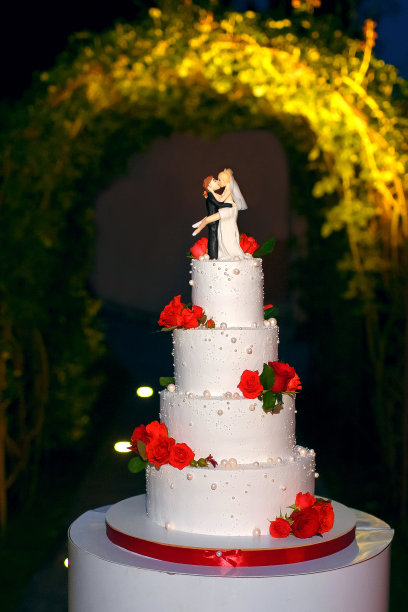 在一个装饰着鲜花的豪华婚礼白色蛋糕上，滑稽的小雕像套房图片下载