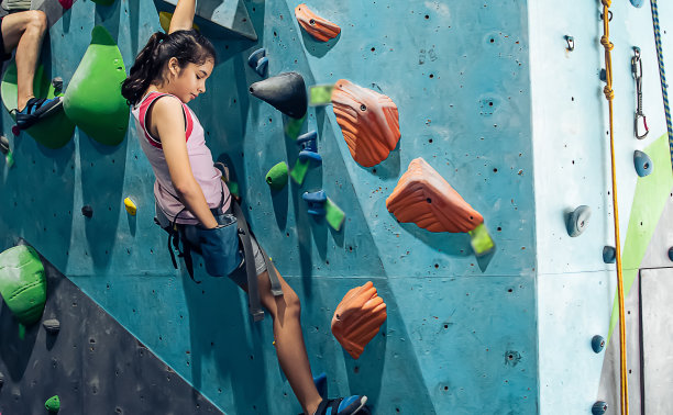 白种人活跃的女孩玩的快乐和攀登岩石山与安全的冒险和运动。活动与教育理念。图片下载