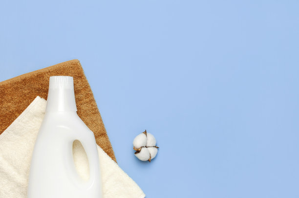 白色塑料包装的洗衣粉，液体粉末，洗涤调理剂，毛巾和棉花花蓝色背景。平躺顶视图复制空间。生物有机产品。生态清洁的概念图片下载