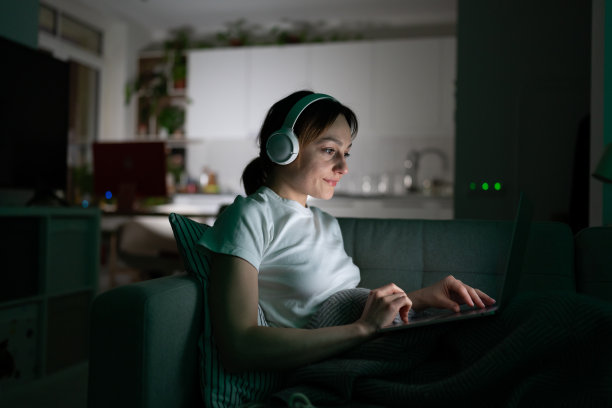 有创意的女人戴着耳机工作音乐，广告项目，晚上看视频和电影图片下载